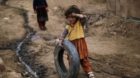 A young Afghan refugee girl plays with a tire in an alley of a poor neighborhood of Rawalpindi, Pakistan, Friday, Feb. 19, 20