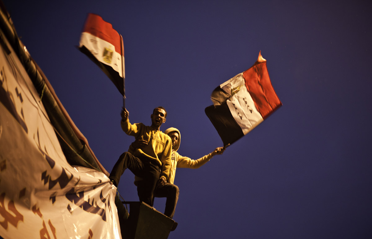 Auf Masten stehend, schwingen zwei Demonstranten Ägyptische Flaggen am Tahrir Square.