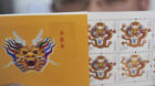 A man shows stamps featuring a dragon at a post office ahead of the Chinese New Year, or the ear of the Dragon, in Jiaxing, i