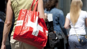 Une femme porte un sac a commissions avec le drapeau suisse apres avoir fait son shopping sur la place de la Palud ce jeudi 7