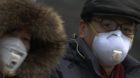 epa03530660 Chinese people walk with masks as heavy smog engulfs the city of Beijing, China 11 January 2013. Thick smog envel
