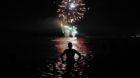 A man watches fireworks as he takes a bath in the Mediterranean Sea on San Juan's (or Saint John's) night, which traditionall