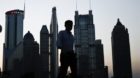 In this photo taken July 10, 2013, a man walks past the downtown skyline of Shanghai, China. China's leaders face new pressur