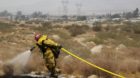 A firefighter works to keep the fire from spreading as the Silver Fire moves into the foothills above Ida Avenue in Cabazon, 