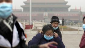 FILE - In this Tuesday, Feb. 25, 2014 file photo, tourists put on their masks after posing for photos as they visit Tiananmen