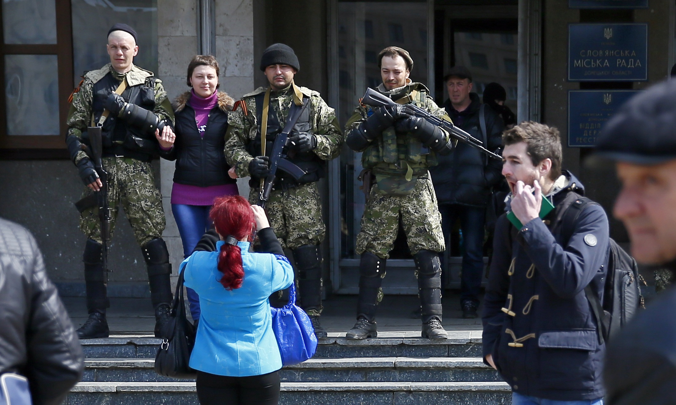 A local resident (2nd L) poses for a picture with pro-Russian armed men standing guard outside the mayor's office in Slaviansk April 14, 2014. Towns in eastern Ukraine on Monday braced for military action from government forces as a deadline passed for pr