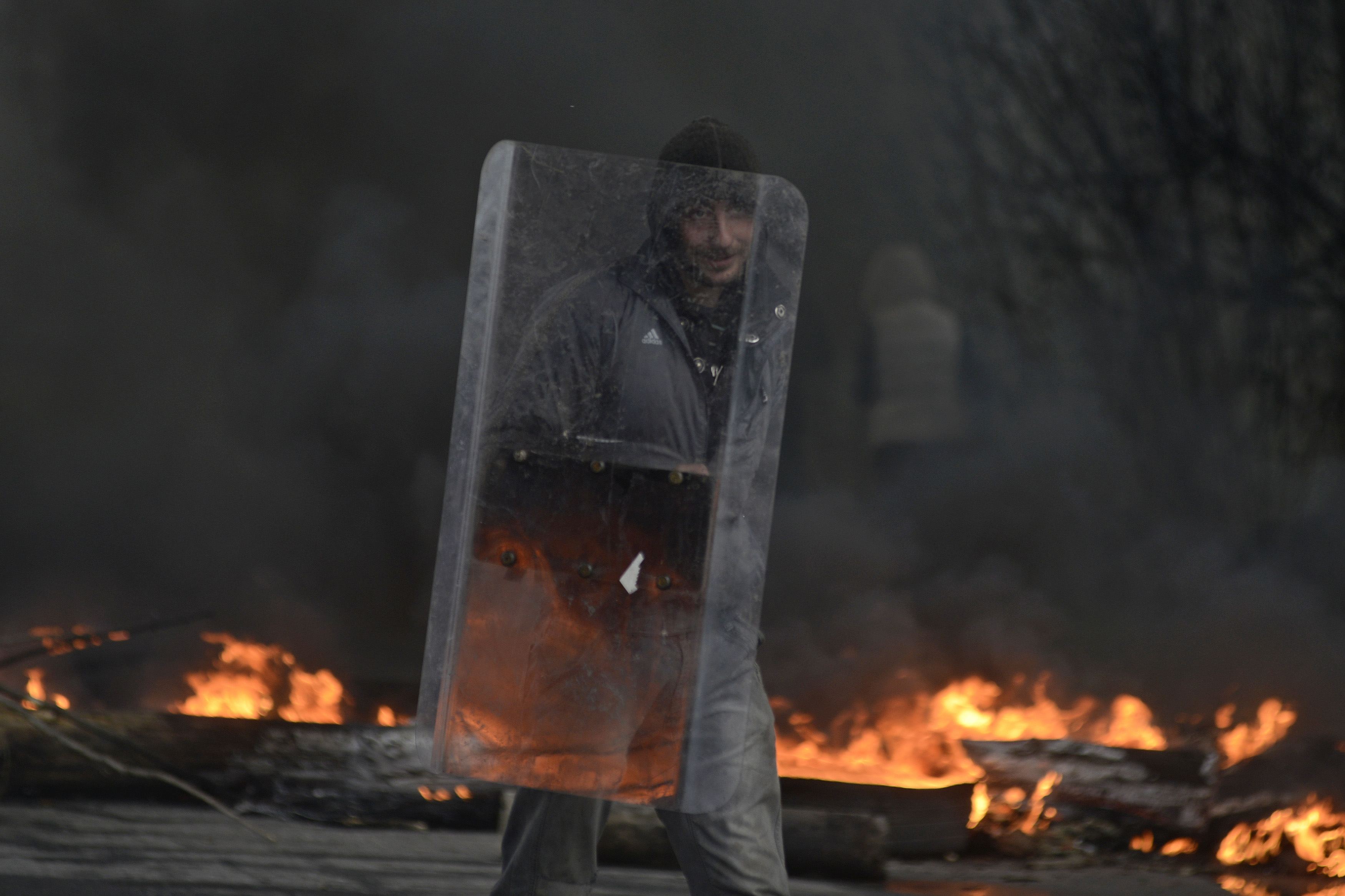 A pro-Russian protester holds a shield at a check point, with black smoke from burning tyres rising above, in Slaviansk April 13, 2014. Ukraine's Interior Minister on Sunday told residents in the eastern city of Slaviansk to stay indoors, in anticipation 