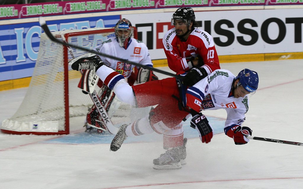 Switzerland's Andreas Ambuehl, center, vies for the puck with Czech's Vojtech Mozik, in front,  during a friendly ice hockey game between Switzerland and Czech Republic, at the St. Jakob Arena in Basel, Switzerland, Sunday, April 27, 2014. (KEYSTONE/Patri