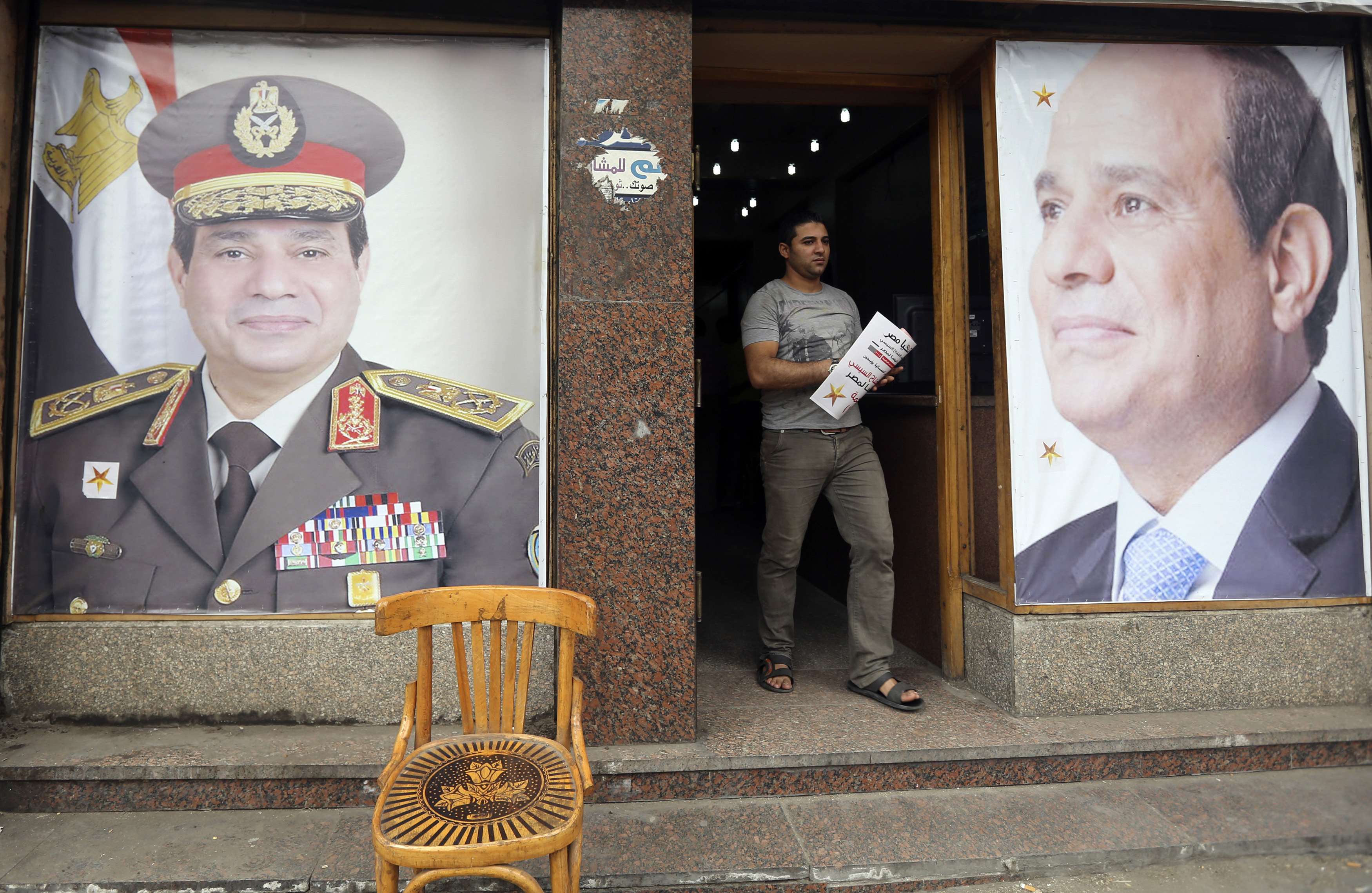 A volunteer leaves the headquarters of former Egyptian army chief Abdel Fattah al-Sisi near his poster in El Gamaliya district, where he spent his childhood, in the old Islamic area of Cairo May 9, 2014. As the Egyptian state presses its crackdown on the 