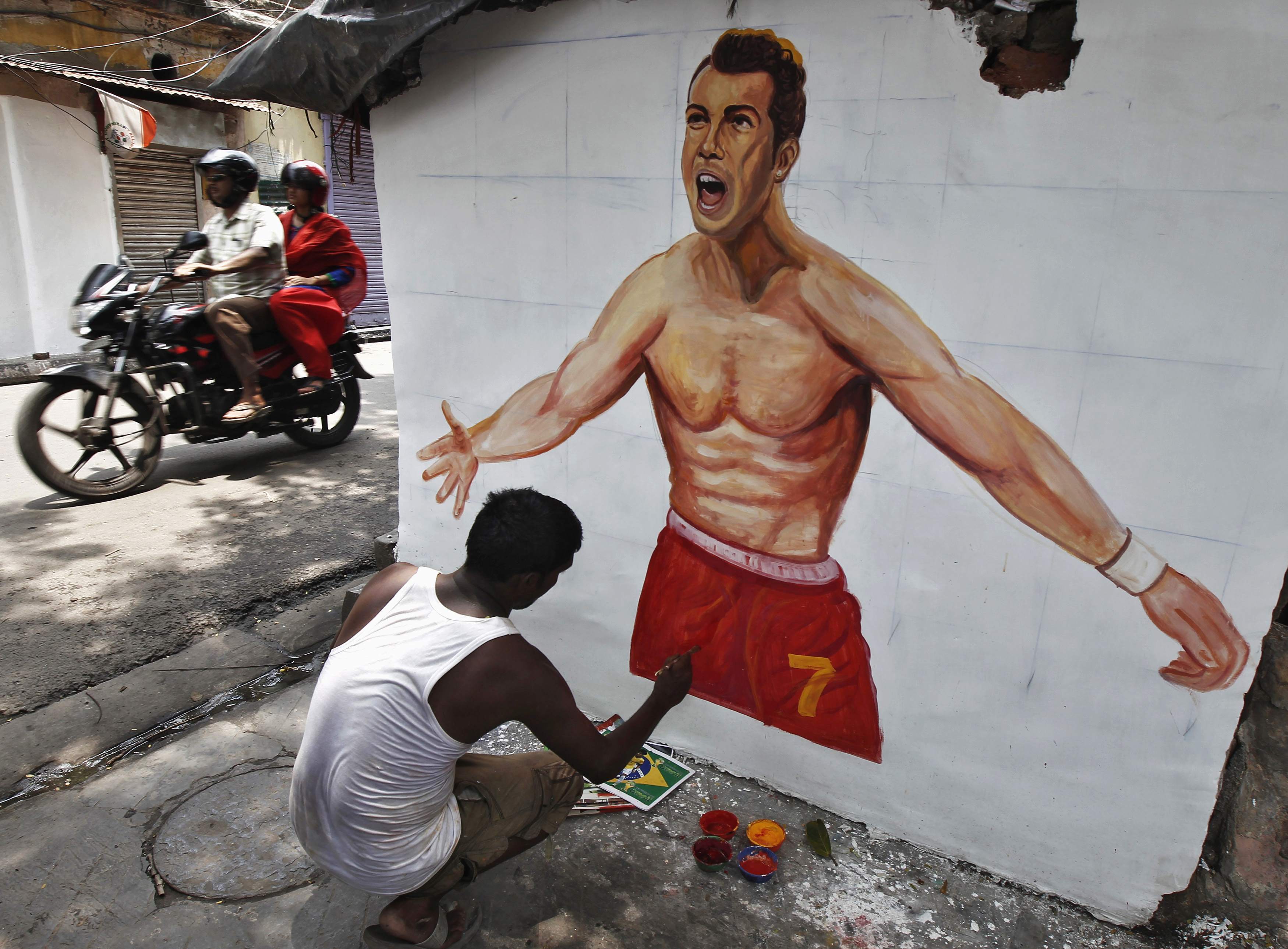 An artisan paints the wall of a house with a picture of Portugal's national soccer player Cristiano Ronaldo, in Kolkata June 12, 2014. The 2014 World Cup soccer tournament will be held in 12 cities in Brazil from June 12 to July 13. REUTERS/Rupak De Chowd