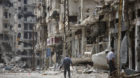 In this Thursday June 5, 2014 photo, men walk through a devastated part of Homs, Syria. Syrian government forces retook the c