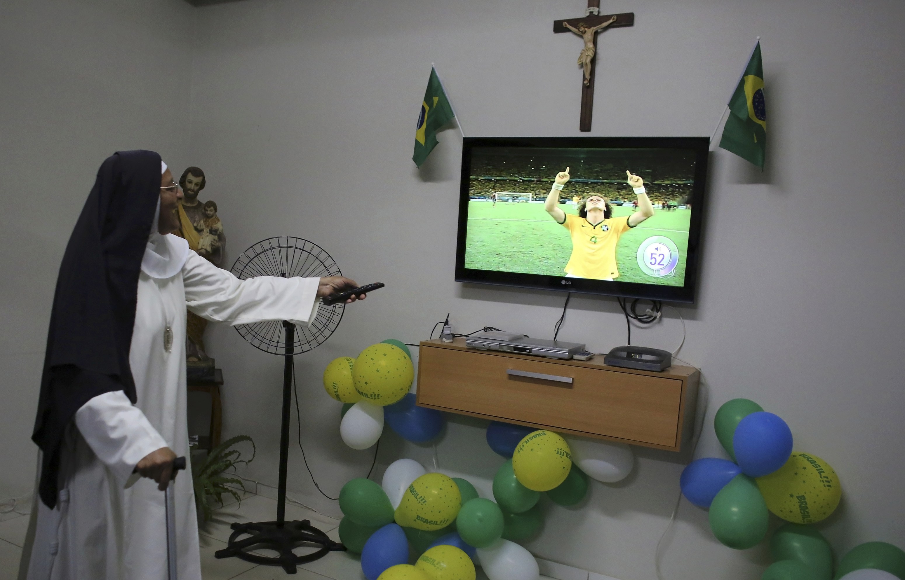 A nun from the enclosed monastery of Imaculada Conceicao watches as Brazil's David Luiz celebrates at the end of the 2014 World Cup quarter-finals between Brazil and Colombia in Piratininga, in the state of Sao Paulo, July 4, 2014.  REUTERS/Nacho Doce (BR