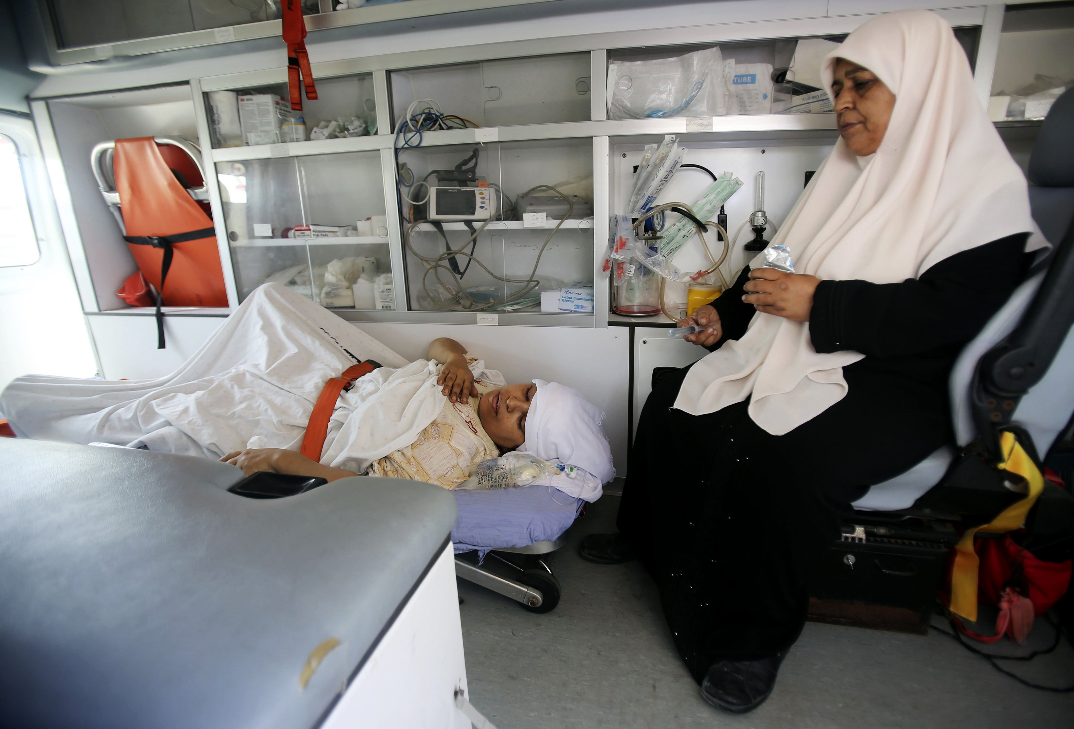 A Palestinian woman, who medics said was wounded in an Israeli air strike, lies on a bed inside an ambulance waiting to cross into Egypt, at Rafah crossing in southern Gaza Strip July 10, 2014. At least 74 Palestinians, most of them civilians, have been k