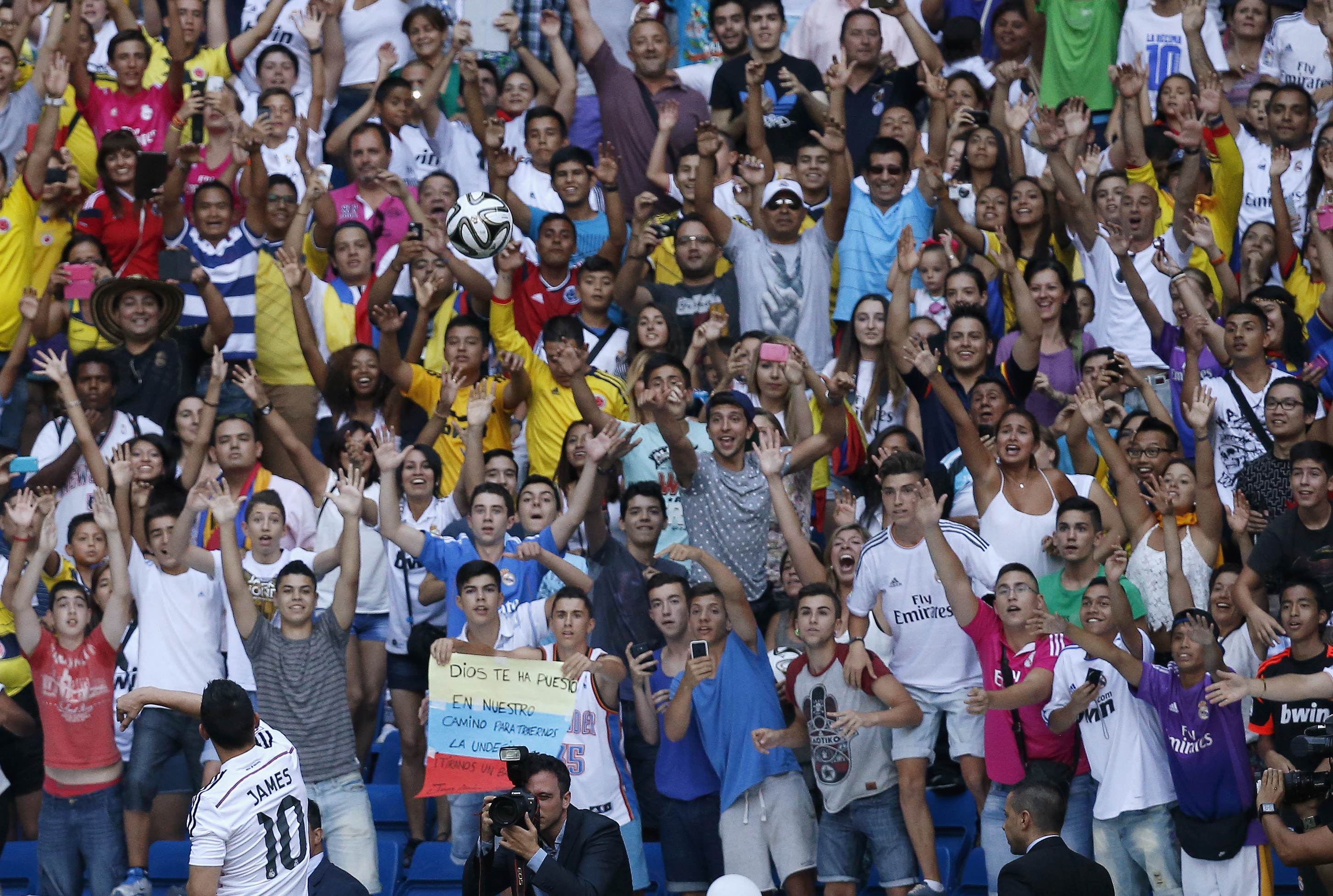 Colombia's soccer player James Rodriguez (L) throws a ball to the fans during his presentation at the Santiago Bernabeu stadium in Madrid, July 22, 2014. Real Madrid have signed Rodriguez from Monaco on a six-year contract, the La Liga club said on Tuesda