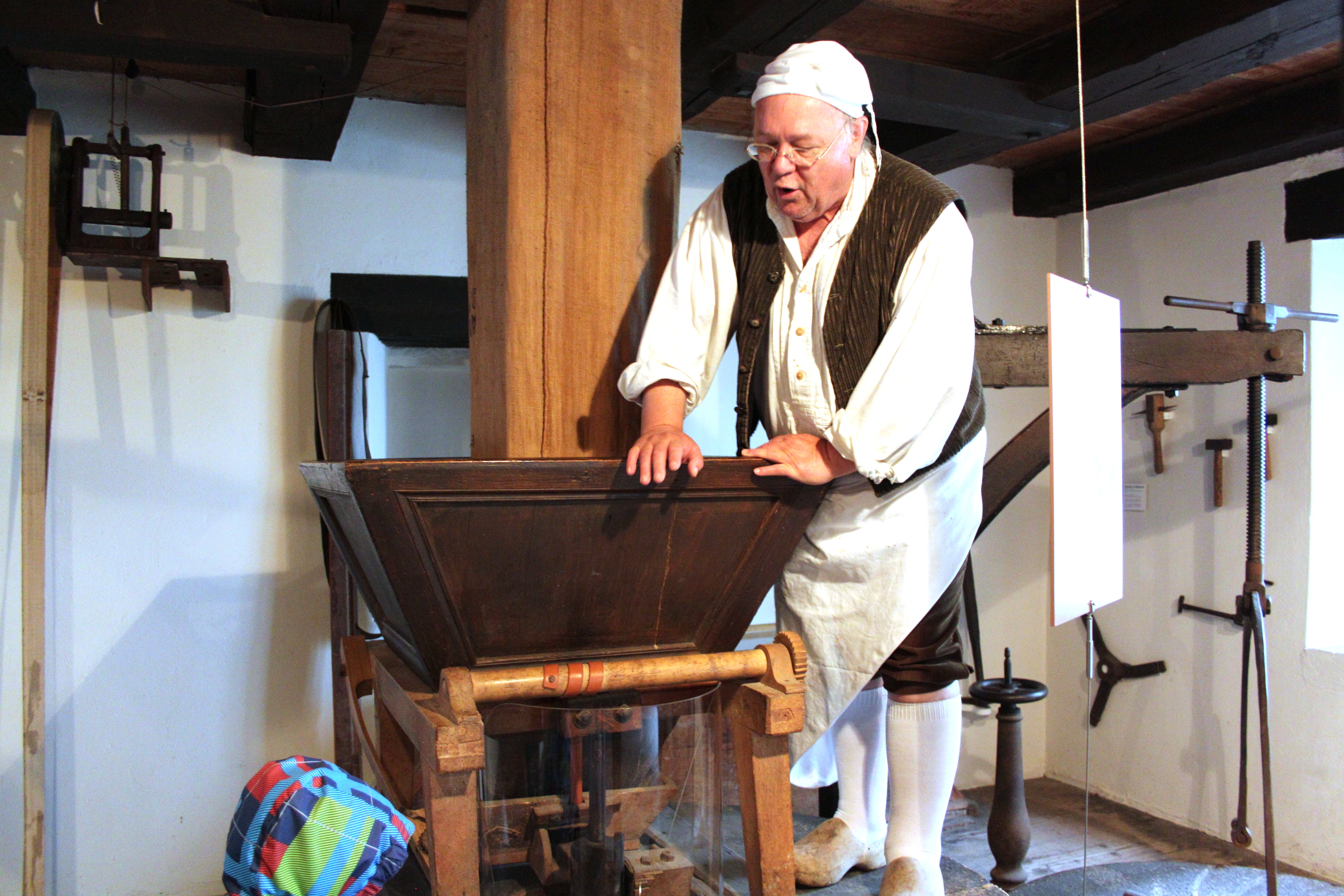 Führung im Mühlenmuseum Brüglingen. Der fleissige Müller zeigt Besuchern den Mühltrichter. 