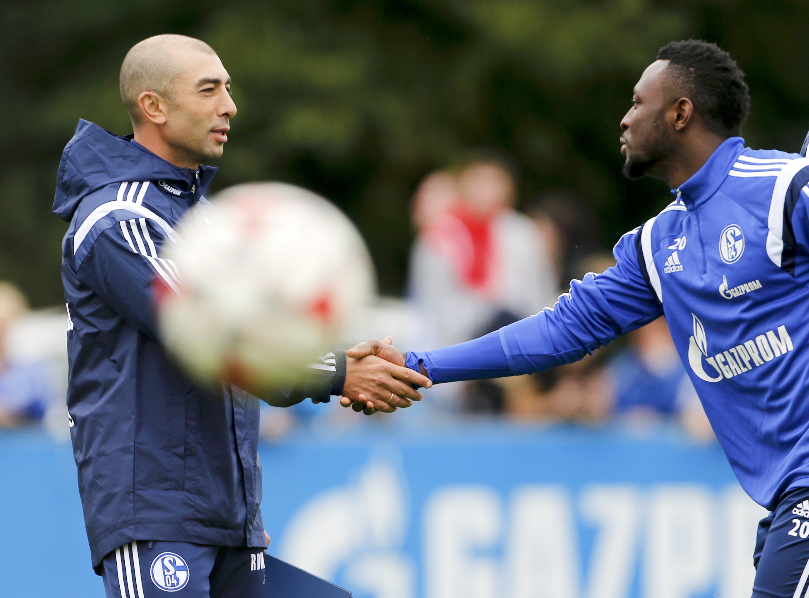 Schalke 04's new coach Roberto Di Matteo shakes hands with player Chinedu Obasi (R) during his first training session as Schalke 04's head coach in Gelsenkirchen September 30, 2014. Schalke 04 appointed Di Matteo, former coach of the 2012 Champions League winner FC Chelsea, as a replacement for Jens Keller, who was sacked on Tuesday after an inconsistent start to the season. REUTERS/Wolfgang Rattay (GERMANY - Tags: SOCCER SPORT)
