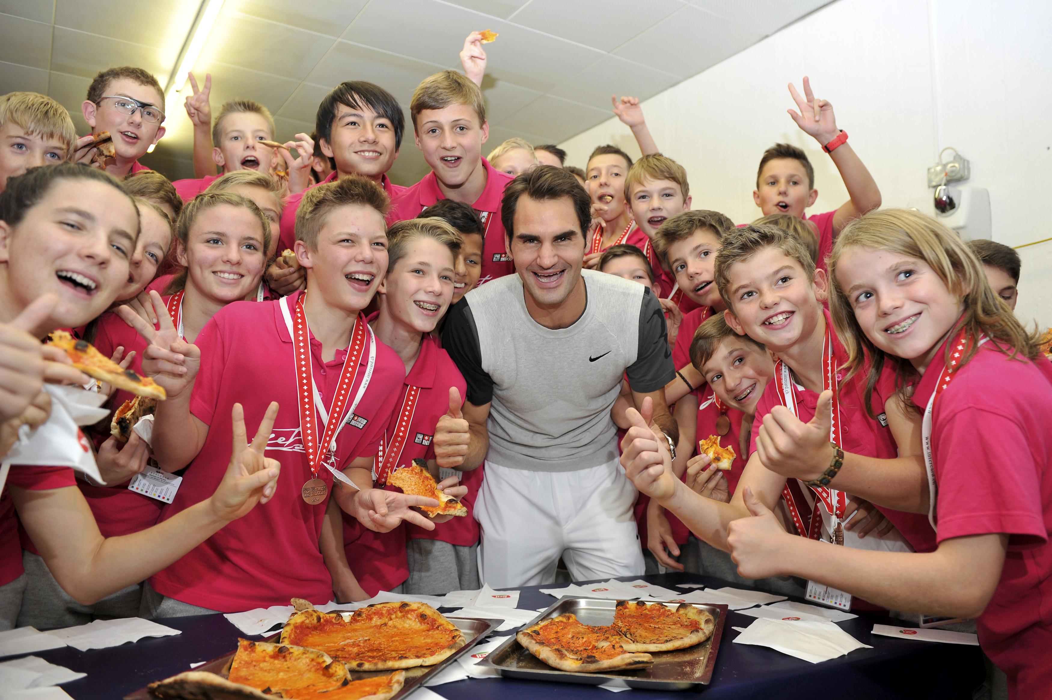 Roger Federer, die obligate Pizza und die Ballkinder der Swiss Indoors in der dritten Variante ihres T-Shirts.