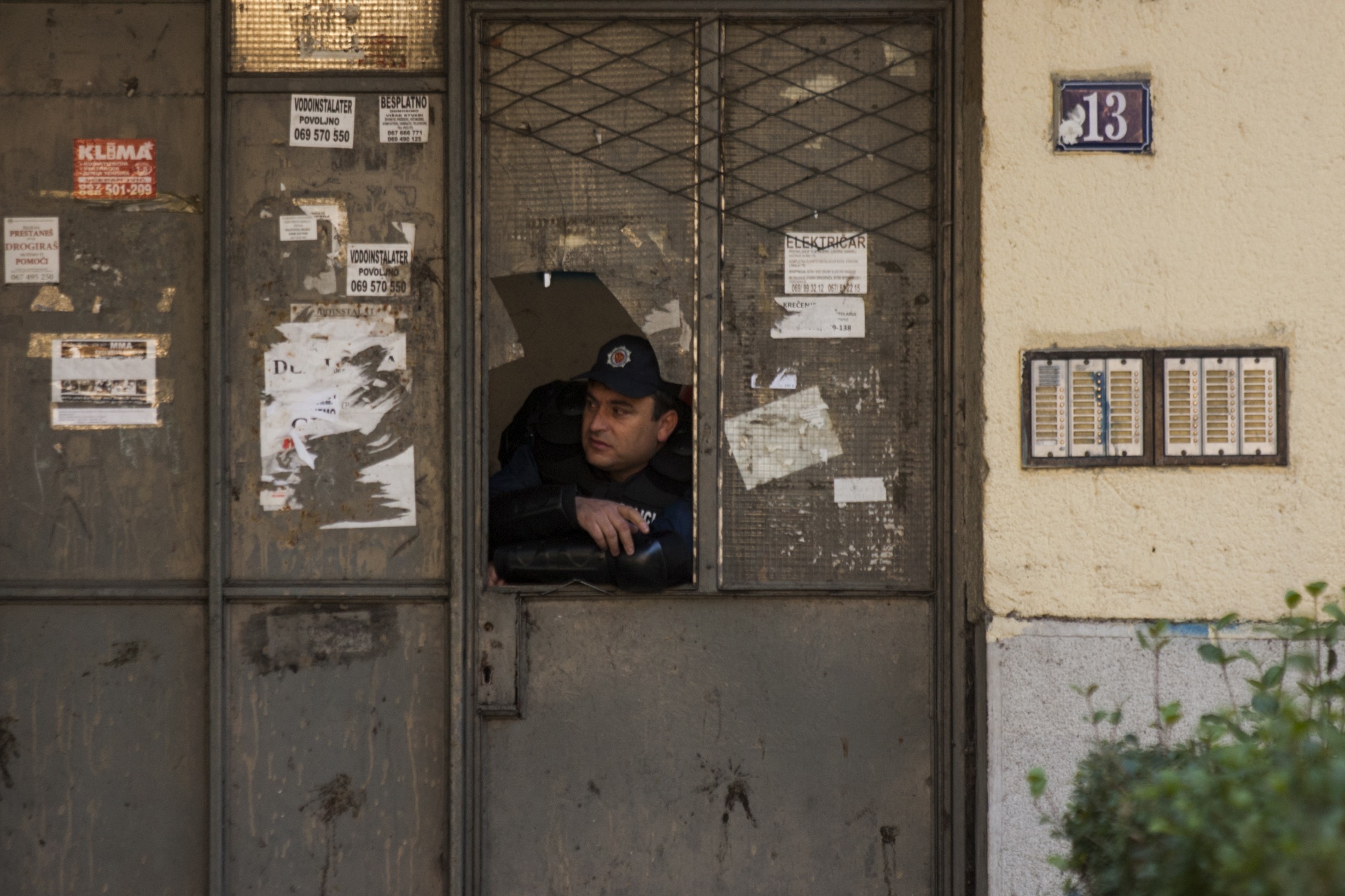 A policeman looks through a broken window near the entrance of a residential building during a Pride March in Podgorica, November 2, 2014. Hundreds of riot police protected about two hundred gay activists who marched peacefully in Montenegro. REUTERS/Stevo Vasiljevic (MONTENEGRO - Tags: SOCIETY)