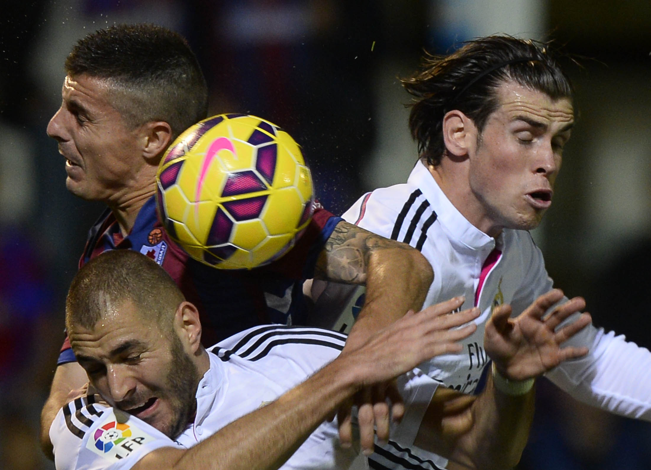 Real Madrid's Karim Benzema (bottom) and Gareth Bale (R) leap for the ball with Eibar's Abraham Minero during their Spanish first division soccer match at Ipurua stadium in Eibar, November 22, 2014. REUTERS/Vincent West (SPAIN - Tags: SPORT SOCCER TPX IMAGES OF THE DAY)