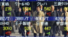 Japanese salarymen crossing a street are reflected on a Tokyo brokerage's stock price board Tuesday, Dec. 18, 2007. The Japan
