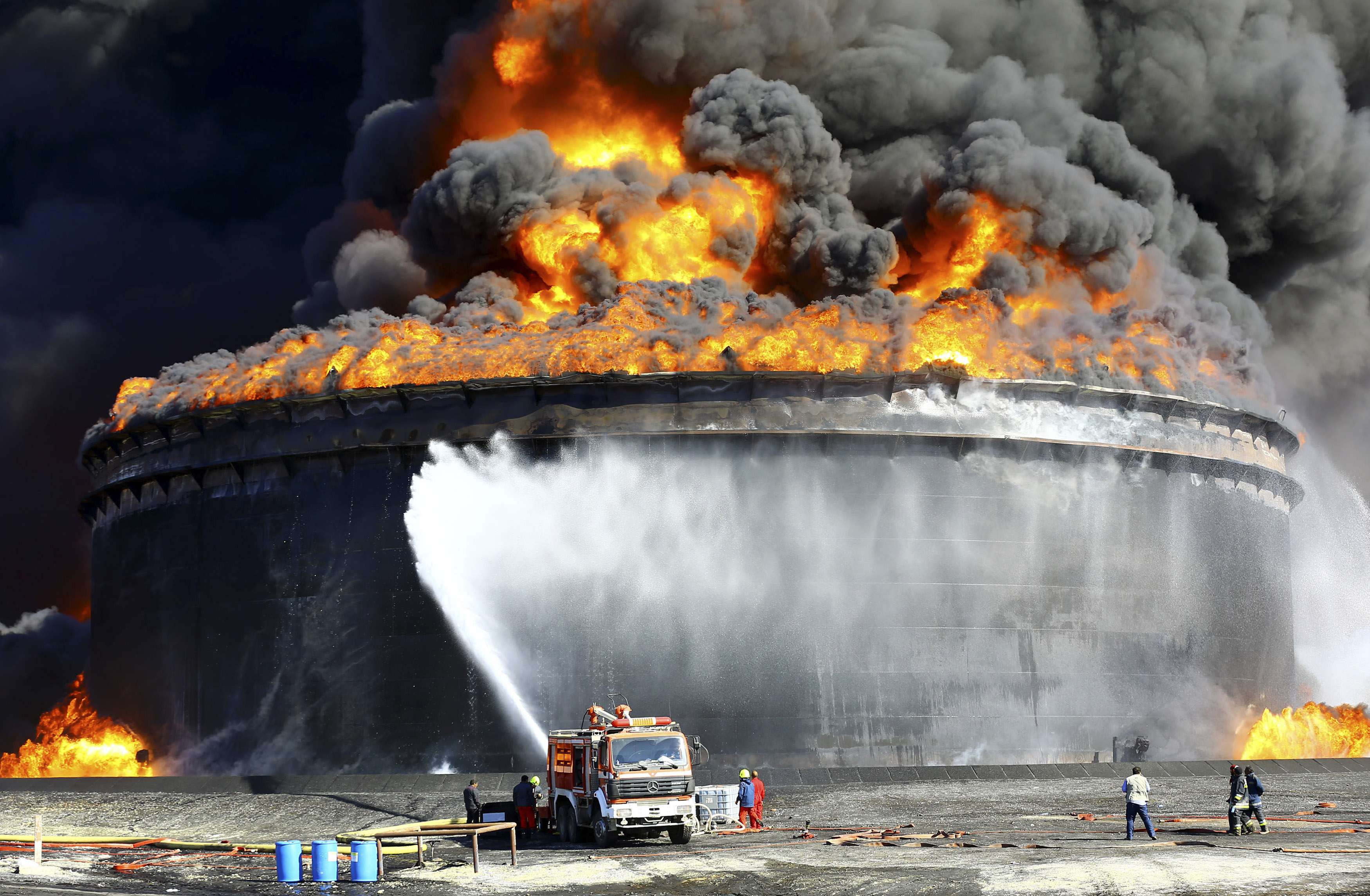 Firefighters work to put out the fire of a storage oil tank at the port of Es Sider in Ras Lanuf December 29, 2014. Oil tanks at Es Sider have been on fire for days after a rocket hit one of them, destroying more than two days of Libyan production, officials said on Sunday. Libya has appealed to Italy, Germany and the United States to send firefighters. REUTERS/Stringer (LIBYA - Tags: CIVIL UNREST POLITICS CONFLICT ENERGY TPX IMAGES OF THE DAY)