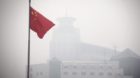epa03022451 The Chinese national flag flames in front of a building barely visible due to heavy smog in Beijing, China, 02 De