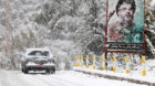 A snow covered taxi drives past a picture of Lebanon's Hezbollah leader Sayyed Hasan Nasrallah in Jbaa village, south Lebanon