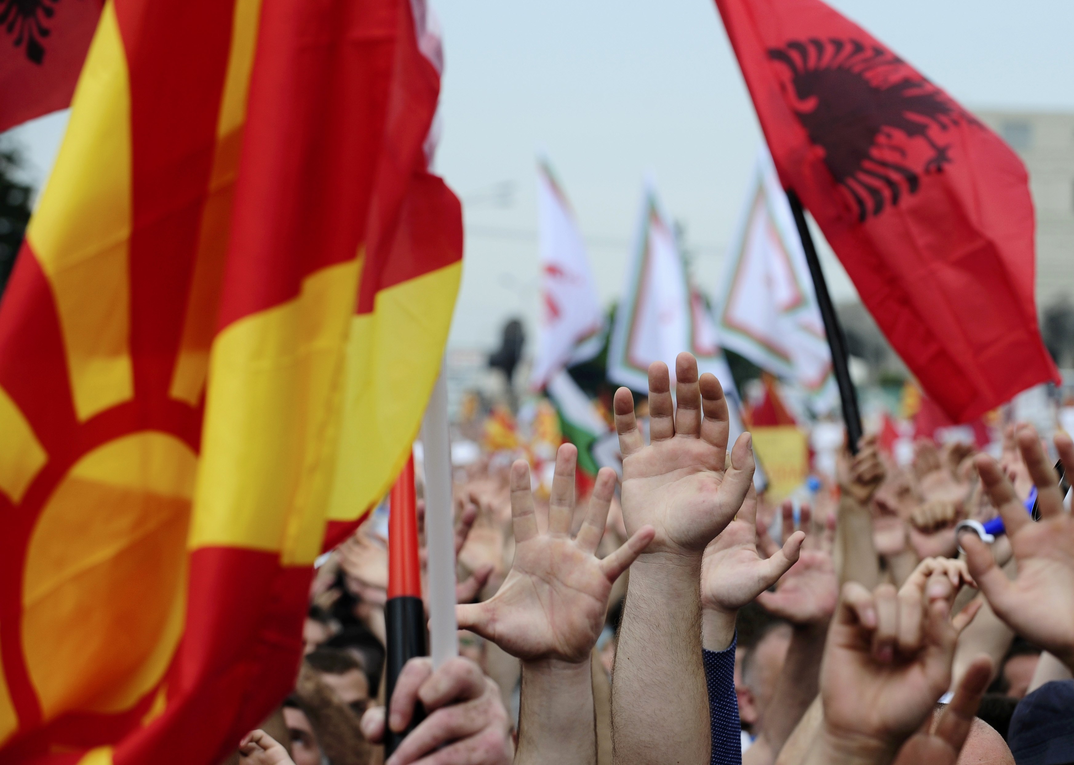 Protesters waving Macedonian and Albanian flags raise their hands during an anti-government demonstration in Skopje, Macedonia, May 17, 2015. Tens of thousands of protesters took to the streets of Macedonia's capital on Sunday, waving Macedonian and Albanian flags in a dramatic display of ethnic unity against a government on the ropes after months of damaging wire-tap revelations. REUTERS/Ognen Teofilovski