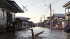 A child jokes in a street flooded by the rising Rio Solimoes, one of the two main branches of the Amazon River, in Anama, Ama