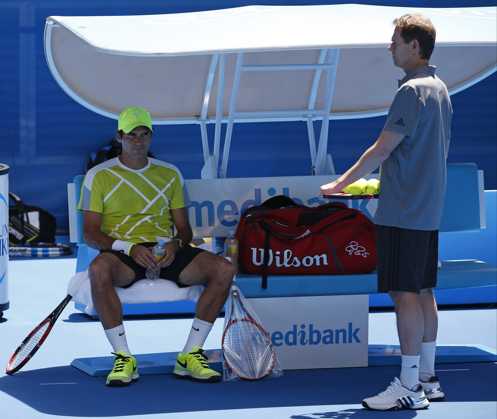 Roger Federer of Switzerland, left, sits in a chair beside coach Stefan Edberg during a training session at the Australian Open tennis championship in Melbourne, Australia, Saturday, Jan. 17, 2015. (AP Photo/Vincent Thian)