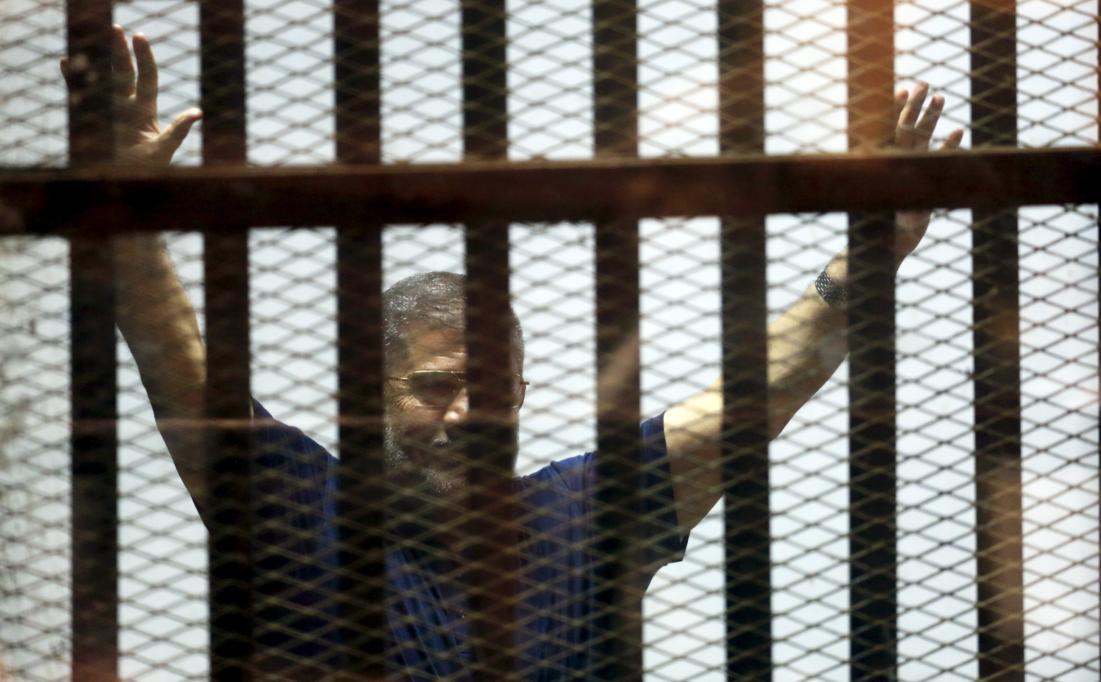 Former Egyptian President Mohamed Mursi waves during his appearance in court on the outskirts of Cairo, Egypt, June 2, 2015. An Egyptian court postponed on Tuesday issuing a final ruling over a death sentence recommendation for former Islamist President Mohamed Mursi and other top Muslim Brotherhood leaders in a case related to a 2011 mass jail break. The judge said the case was postponed to June 16. REUTERS/Amr Abdallah Dalsh
