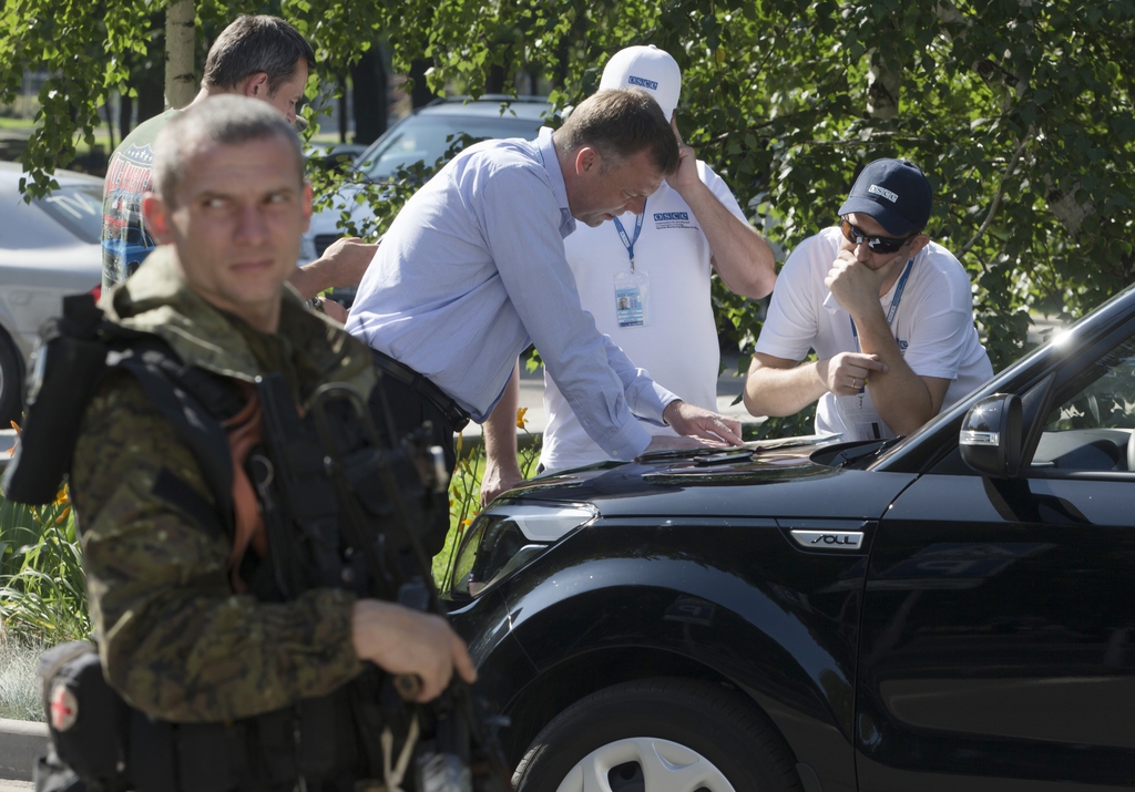Alexander Hug, deputy head of the OSCE mission to Ukraine, center, and his colleagues examine a map as they discuss the situation around the site of the crashed Malaysia Airlines Flight 17, in the city of Donetsk, eastern Ukraine Wednesday, July 30, 2014. (AP Photo/Dmitry Lovetsky)