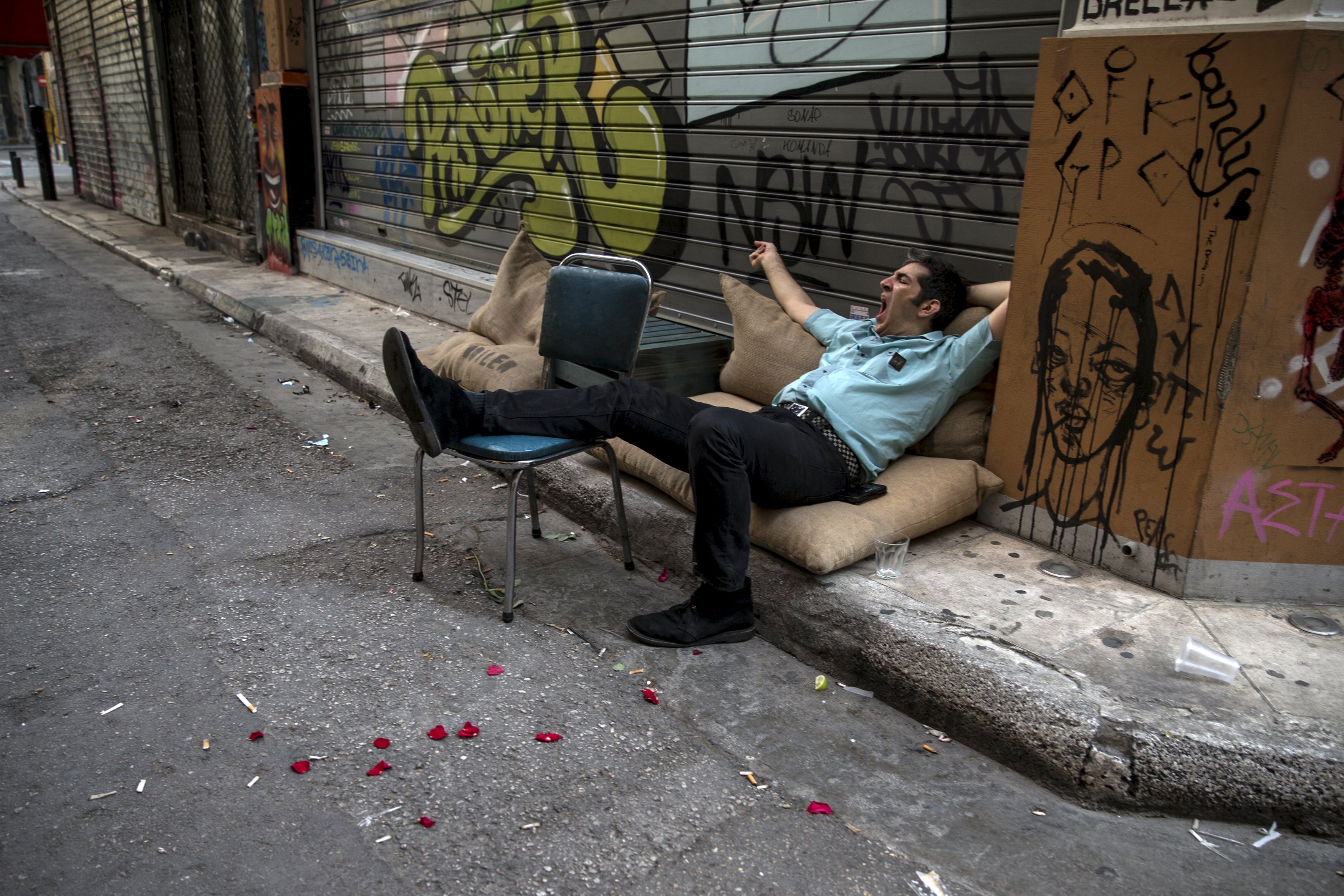 A man yawns while resting on a street in Athens, Greece June 28, 2015. Greece's European partners shut the door on extending a credit lifeline to Athens, leaving the country facing a default that could push it out of the euro and cause ripple effects across the European economy and beyond. REUTERS/Marko Djurica