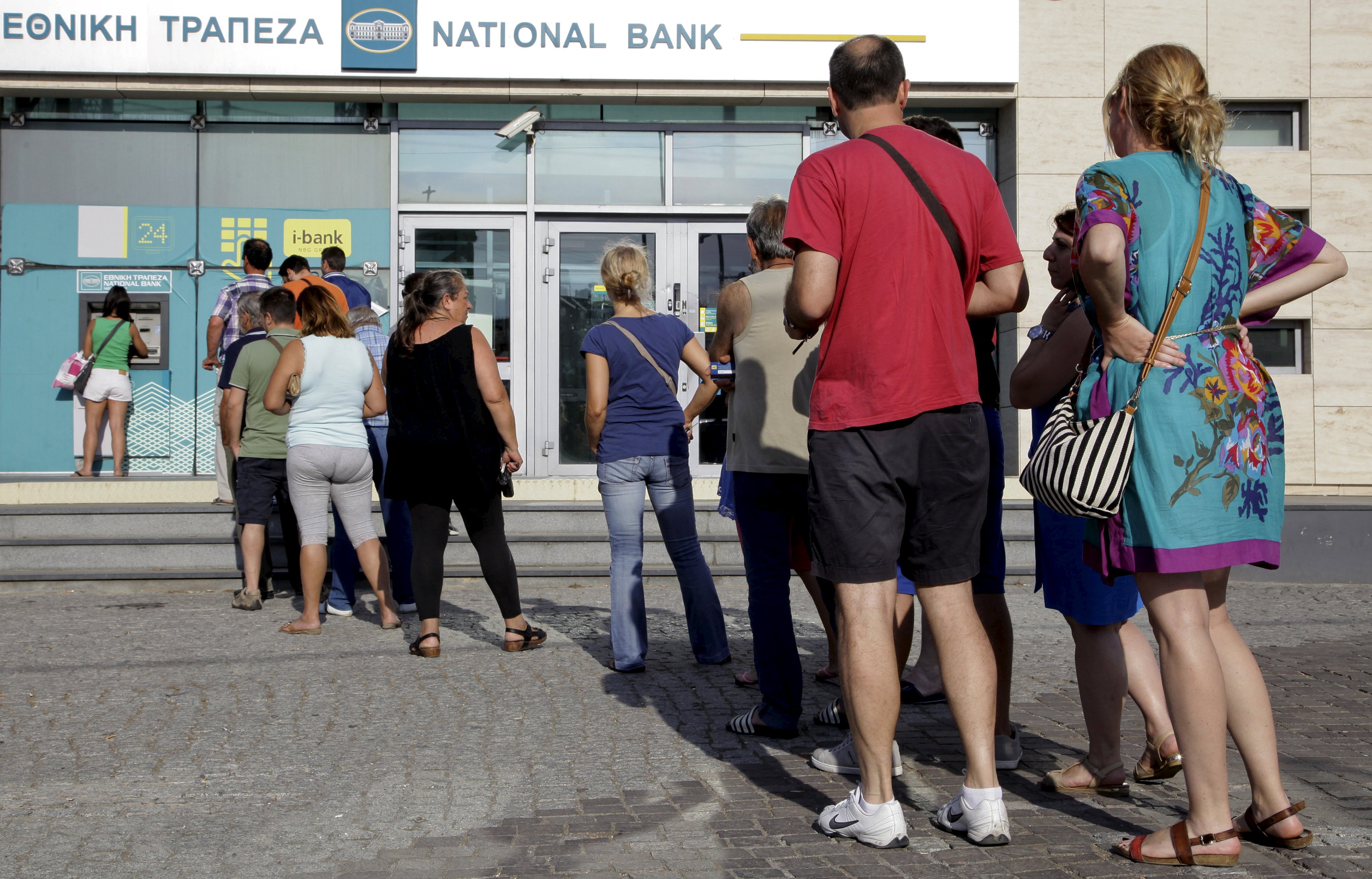People line up to withdraw cash from an automated teller machine (ATM) outside a National Bank branch in Iraklio on the island of Crete, Greece June 28, 2015. Greece's Prime Minister Alexis Tsipras on Sunday announced a bank holiday and capital controls after Greeks responded to his surprise call for a referendum on bailout terms by pulling money out of banks. REUTERS/Stefanos Rapanis