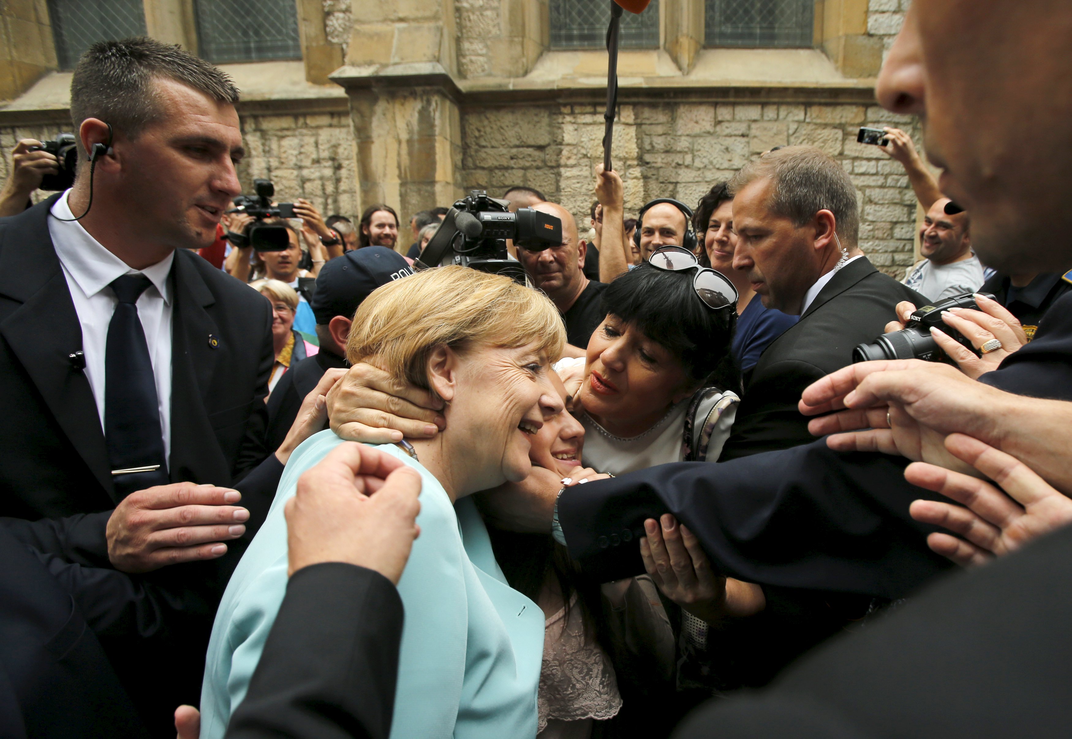 A woman tries to kiss German Chancellor Angela Merkel after she visited the Srebrenica exhibition in downtown of Sarajevo, Bosnia and Herzegovina, July 9, 2015. REUTERS/Antonio Bronic