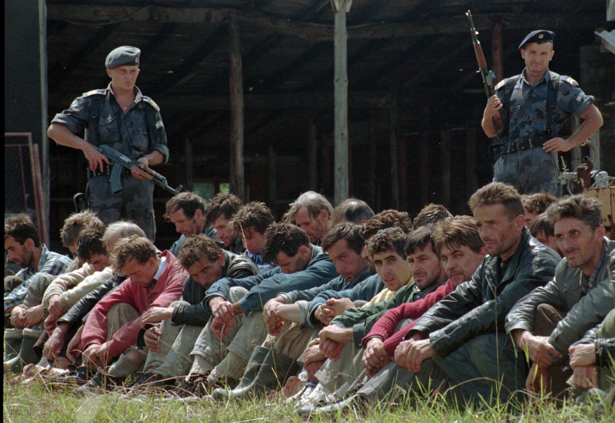 Two Serbian policemen guard a group of Bosnian Muslim men from the Srebrenica enclave that have crossed into Yugoslavia from Bosnia in the Serb town of Uzice,some 250km (155 miles) south of Belgrade Saturday Aug. 5.1995. Several hundred Bosnian Muslim men crossed the Drina river which divides Yugoslavia and Bosnia.(AP PHOTO)
