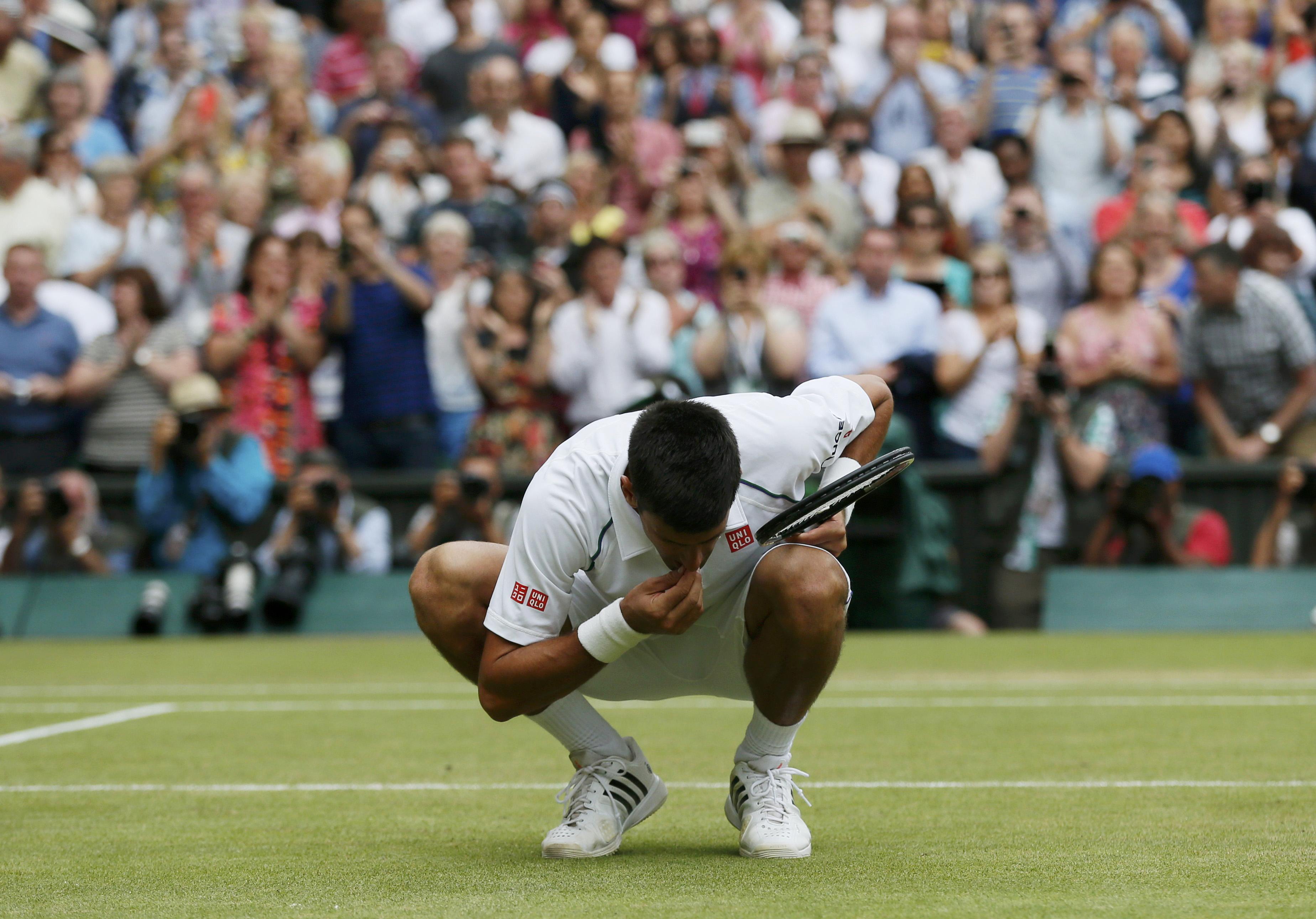 Novak Djokovic of Serbia eats some grass off Centre Court after winning his Men's Singles Final match against Roger Federer of Switzerland at the Wimbledon Tennis Championships in London, July 12, 2015. REUTERS/Stefan Wermuth