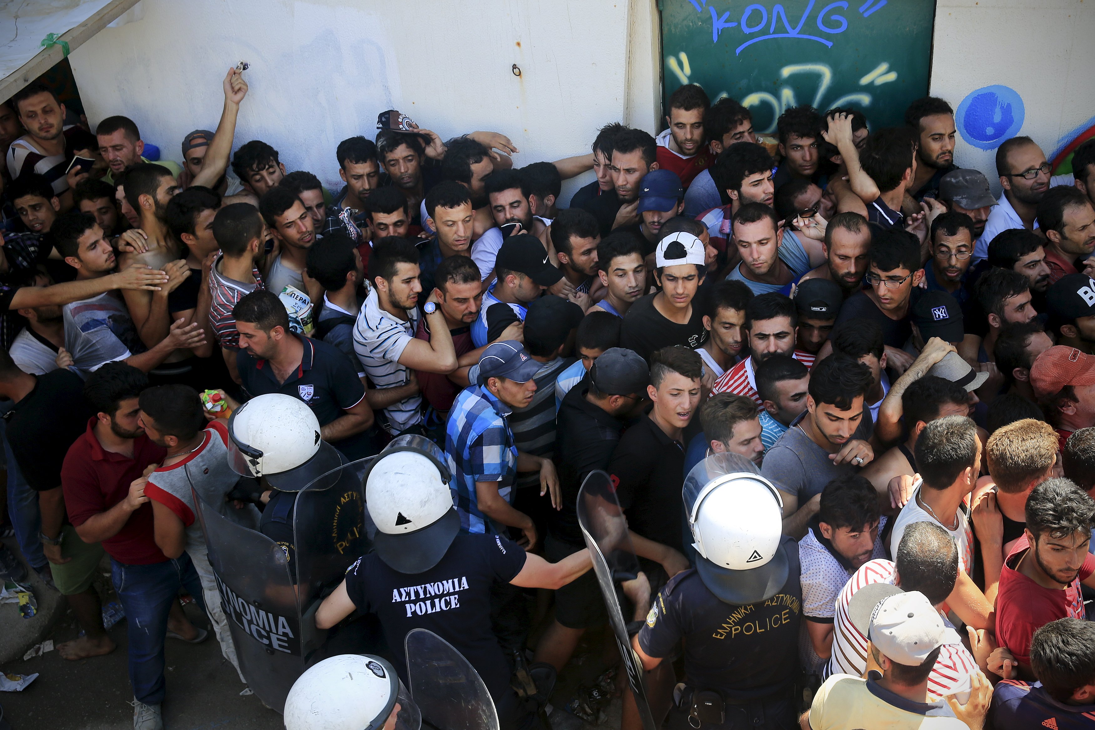 Migrants and refugees are pushed as riot police try to maintain an orderly line during a registration procedure at the national stadium of the Greek island of Kos, August 12, 2015. The United Nations refugee agency (UNHCR) called on Greece to take control of the 