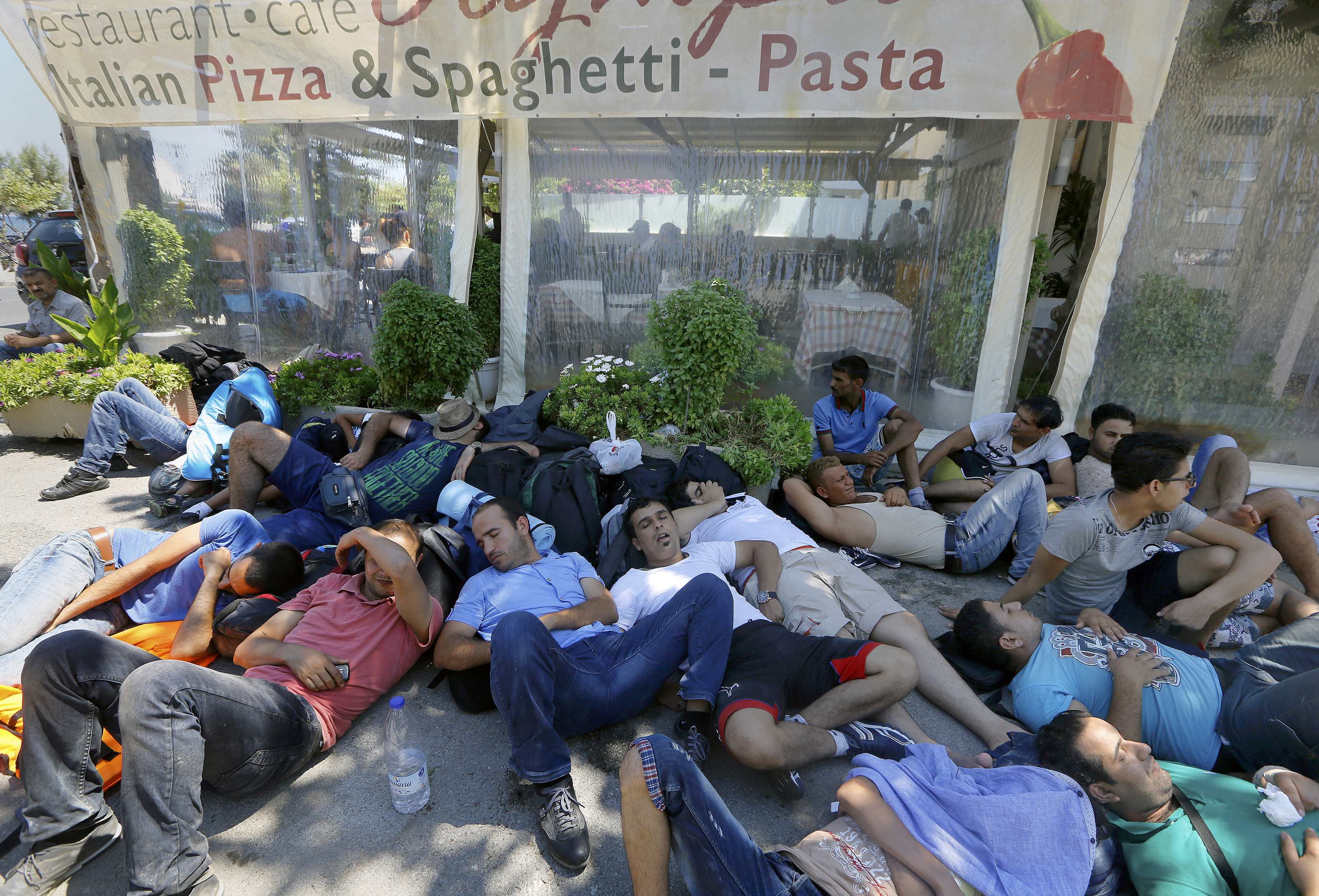 Syrian refugees rest on a street as they are wait for registration outside the stadium in the Greek island of Kos August 13, 2015. The United Nations refugee agency (UNHCR) called on Greece to take control of the 