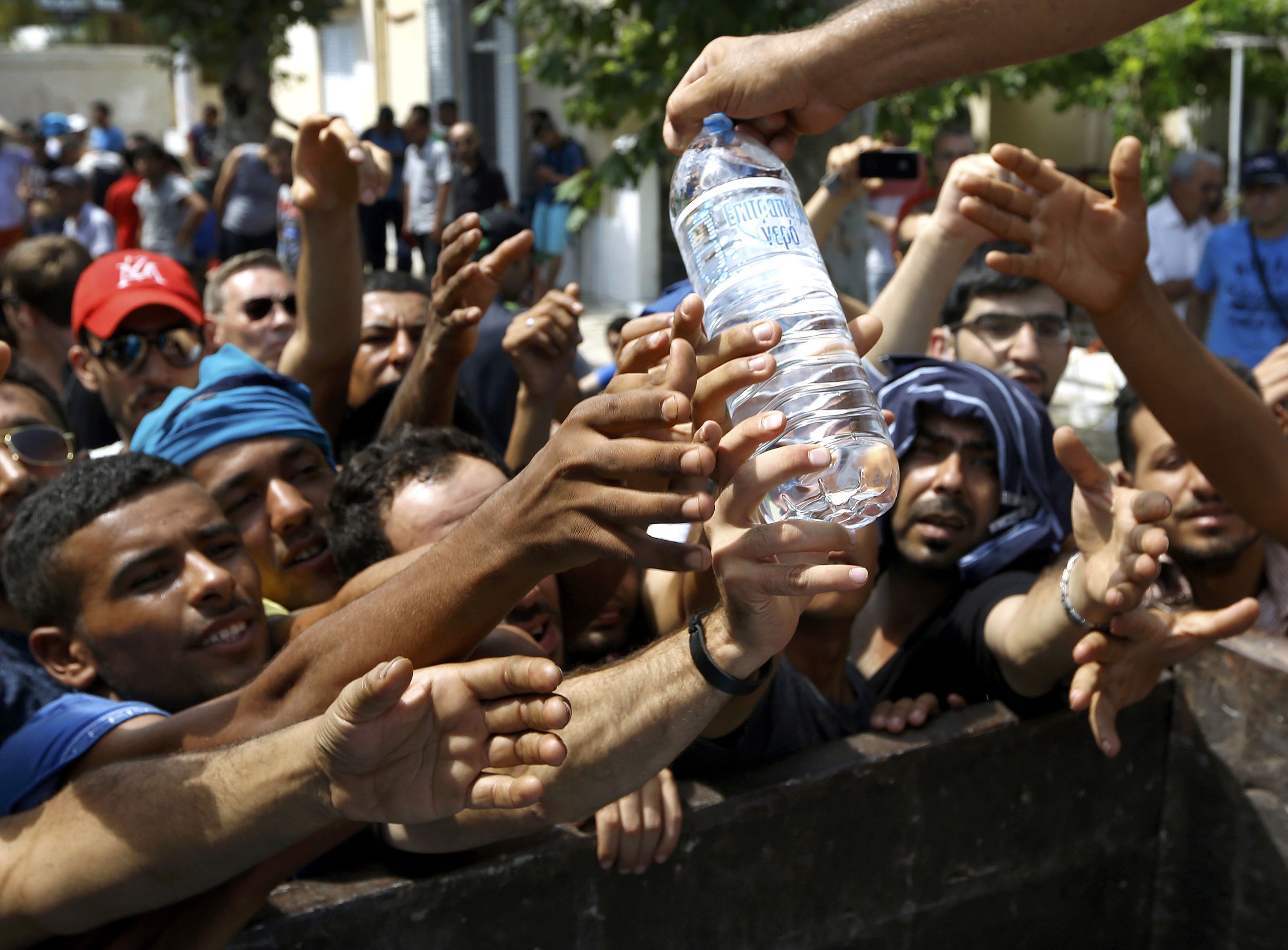 Syrian refugees and other migrants struggle to get water during aid distribution by workers of the Kos municipality on the Greek island of Kos August 14, 2015. United Nations refugee agency (UNHCR) called on Greece to take control of the 