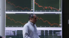 Beschäftigte der Börse in Athen laufen an einer Tafel mit der Kursentwicklung vorbei. (Archivbild)