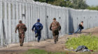 A migrant crosses the boarder fence as soldiers and police try to catch him clo to a migrant collection point in Roszke, Hung