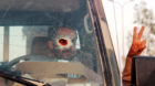 A Yemeni soldier, pictured through a vehicle's windscreen, which was damaged by a bullet, gestures out of the window, in Mari