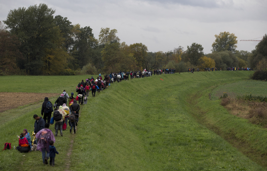 Migrants walk on a dyke after crossing from Croatia, in Brezice, Slovenia Monday, Oct. 19, 2015. Croatia's interior minister has rejected Slovenia's accusations that Croatia broke an agreement on limiting the numbers crossing their border to 2,500 a day, saying the Slovenes have kept changing the figure. (AP Photo/Darko Bandic)