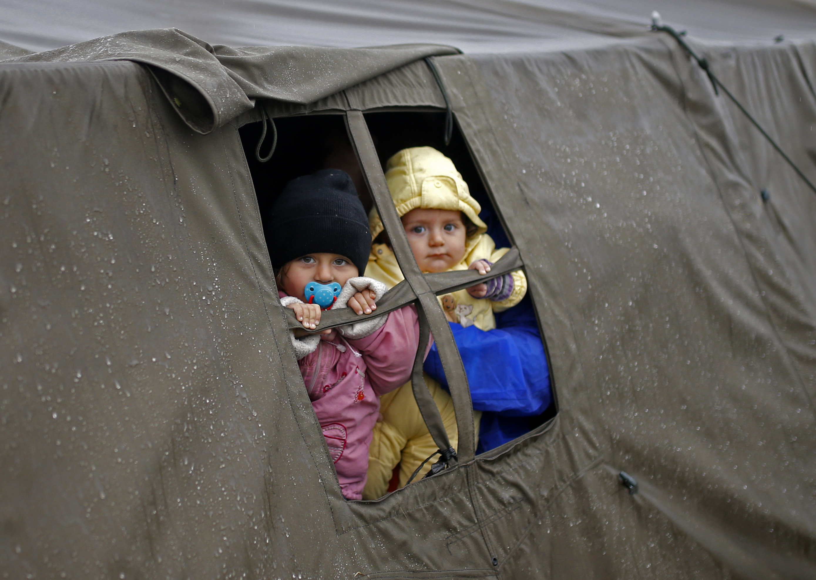 Children look out from a tent at a migrant camp in Opatovac, Croatia October 19, 2015. The Balkans struggled with a growing backlog of migrants on Monday after Hungary sealed its southern border and Slovenia tried to impose a limit, leaving thousands stranded on cold, wet borders where tempers frayed. More than 10,000 were stranded in Serbia, the United Nations refugee agency (UNHCR) said, with more on the way but nowhere to go. REUTERS/Dado Ruvic