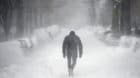 A man walks along a street covered by snow during a winter storm in Washington January 23, 2016. A winter storm dumped nearly