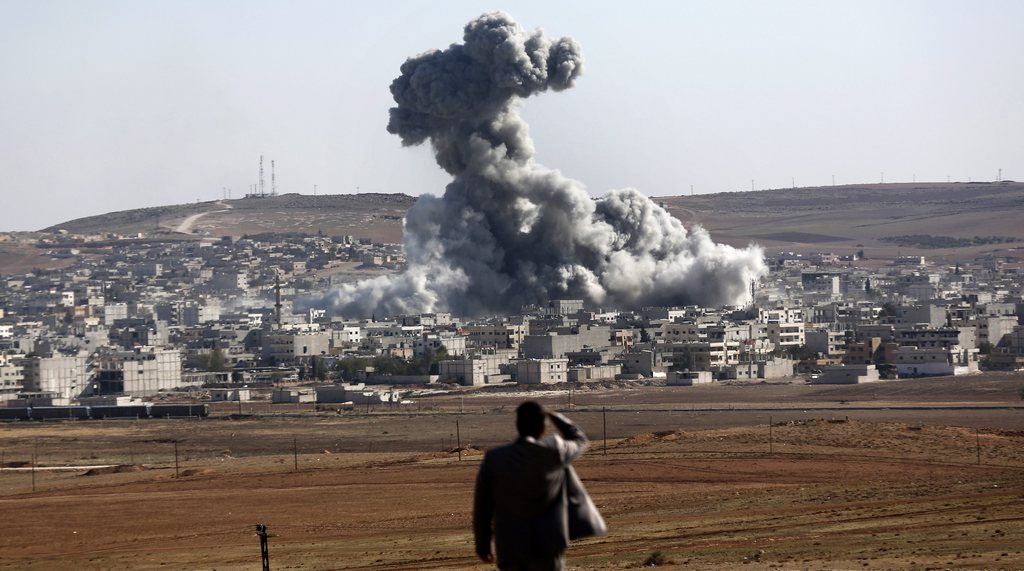 epa04457553 A man watches an explosion after an apparent US-led coalition airstrike on Kobane, Syria, as seen from the Turkish side of the border, near Suruc district, Sanliurfa, Turkey, 22 October 2014. Meanwhile, the Pentagon said it was possible that weapons delivered by the US military and meant for Kurdish fighters in Kobane, a Syrian Kurdish city near the Turkish border, may have inadvertently fallen into the hands of Islamic State (IS) militants. EPA/SEDAT SUNA
