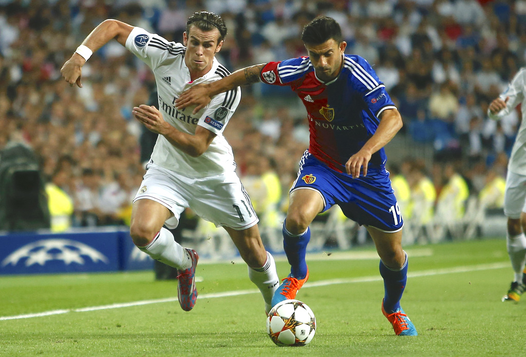 Real's Gareth Bale vies for the ball with Basel's Behrang Safari during the Champions League Group B soccer match between Real Madrid and Basel at the Santiago Bernabeu stadium in Madrid, Spain, Tuesday, Sept. 16, 2014. (AP Photo/Andres Kudacki)