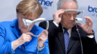 German Chancellor Angela Merkel and Swiss President Johann Schneider-Ammann (R) look at head-mounted display units on the Bro