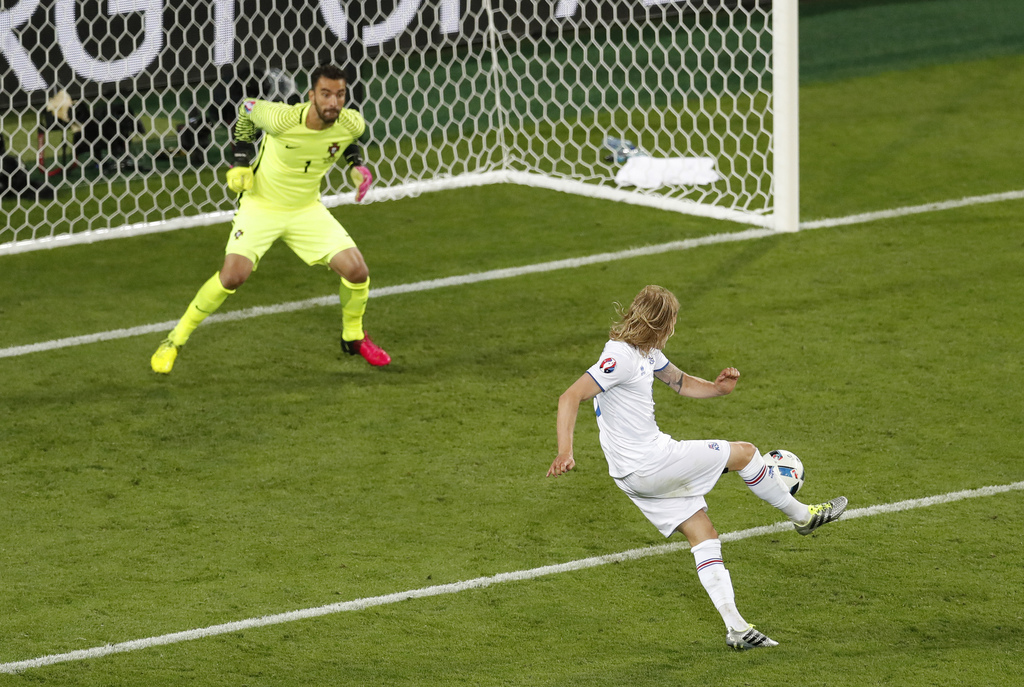 Iceland's Birkir Bjarnason, right, shoots and scores an equalizer in front of Portugal goalkeeper Rui Patricio, during the Euro 2016 Group F soccer match between Portugal and Iceland at the Geoffroy Guichard stadium in Saint-Etienne, France, Tuesday, June 14, 2016. (AP Photo/Michael Sohn)